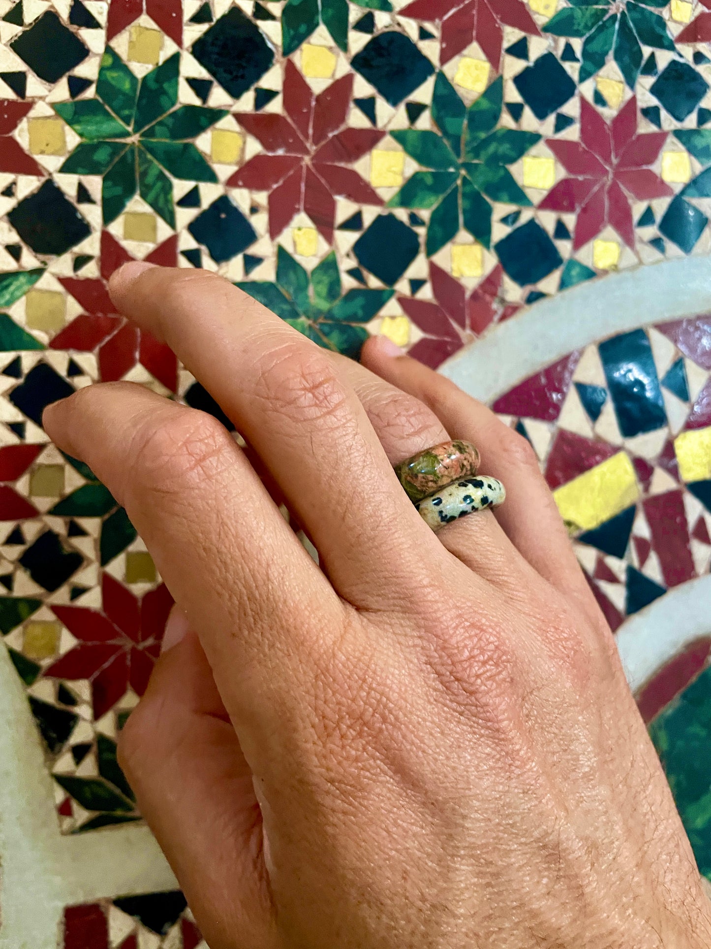 unakite and dalmatian jasper rings on male model with byzantine arab mosaic in background.