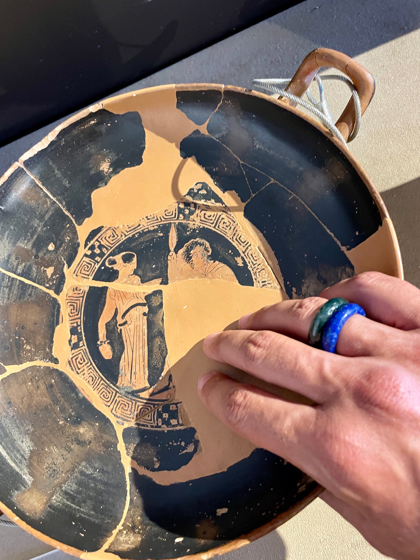 moss agate and royal lapis lazuli rings paired on a male model while he's holding ancient greek pottery.