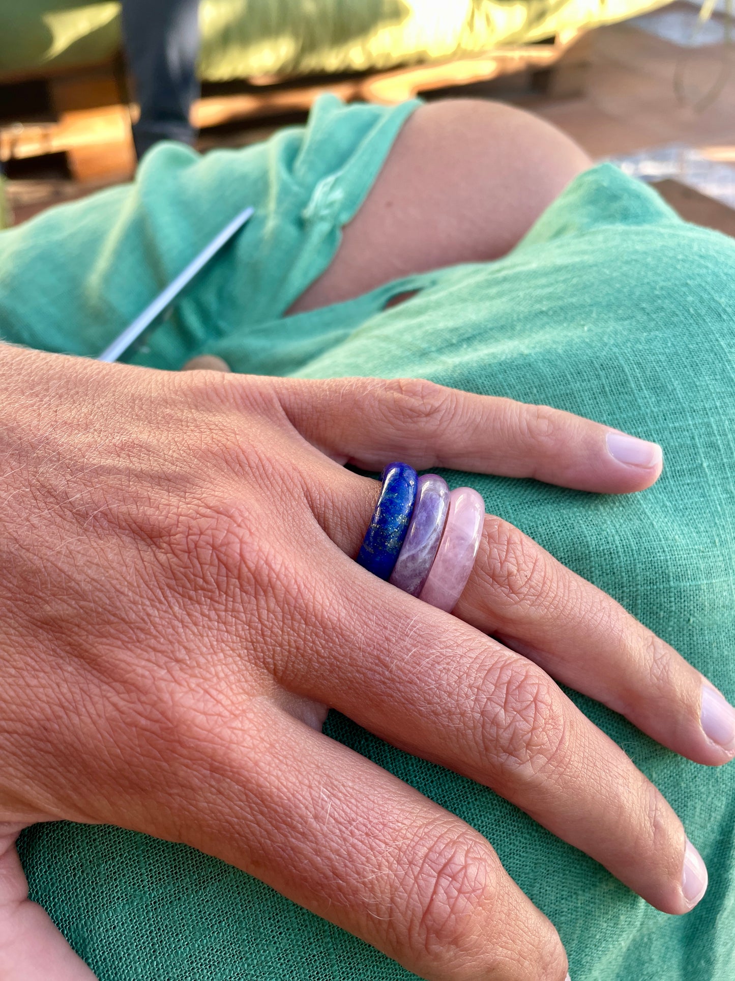 royal lapis lazuli, amethyst, and rose quartz rings paired together on a female model with her hand resting on her green dress.