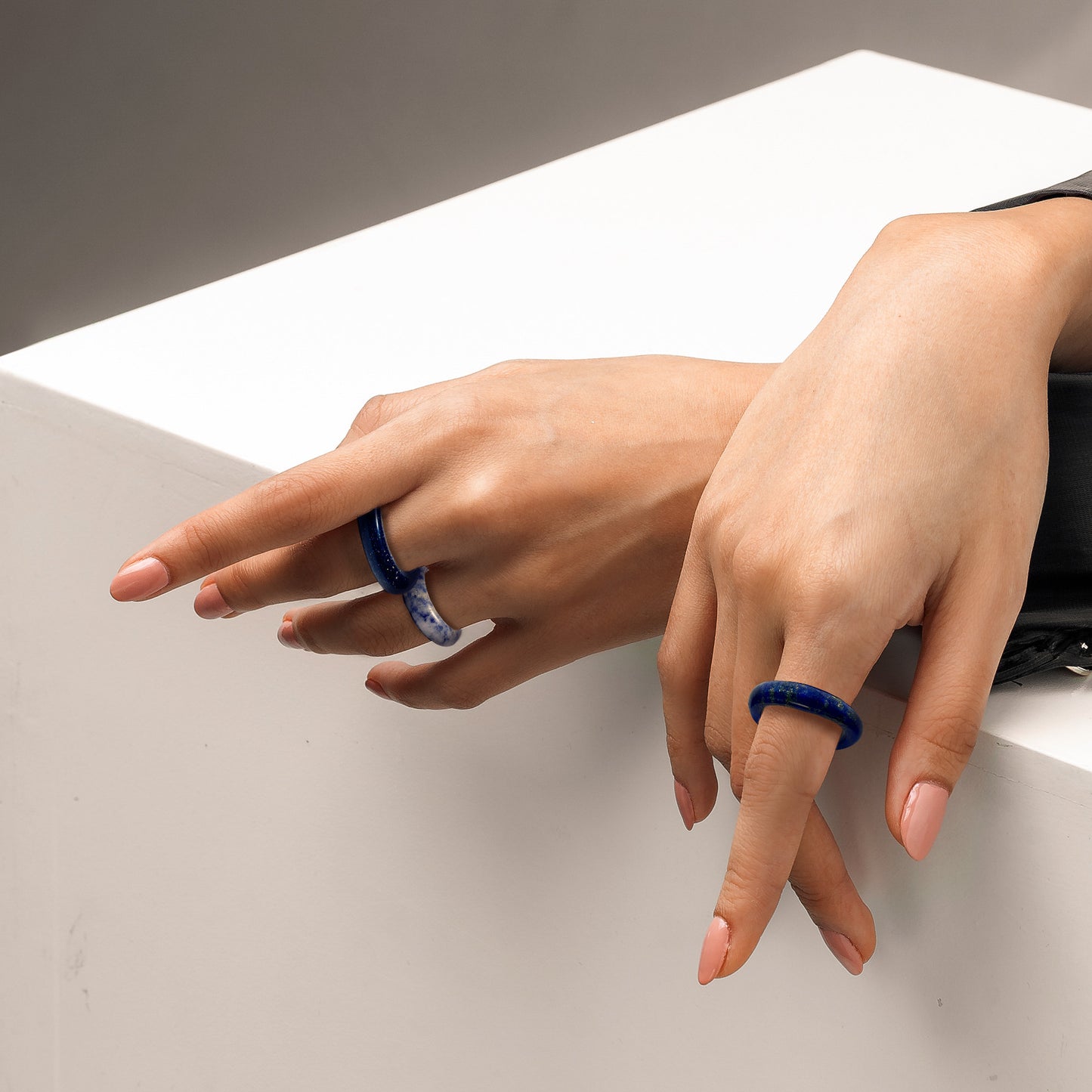 royal lapis lazuli and blue sandstone rings on a woman's hands, posed on a white display box, by whitestone jewelry co.