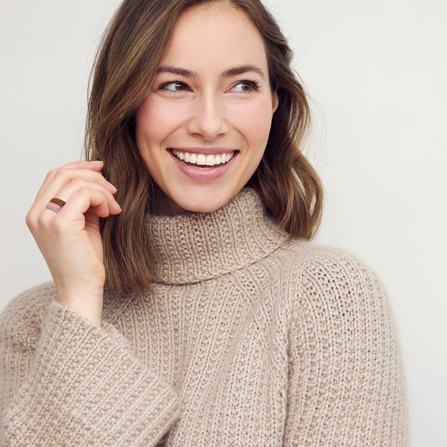 smiling woman wearing the frida rose quartz and toltec tiger's eye stone band rings by whitestone jewelry co.