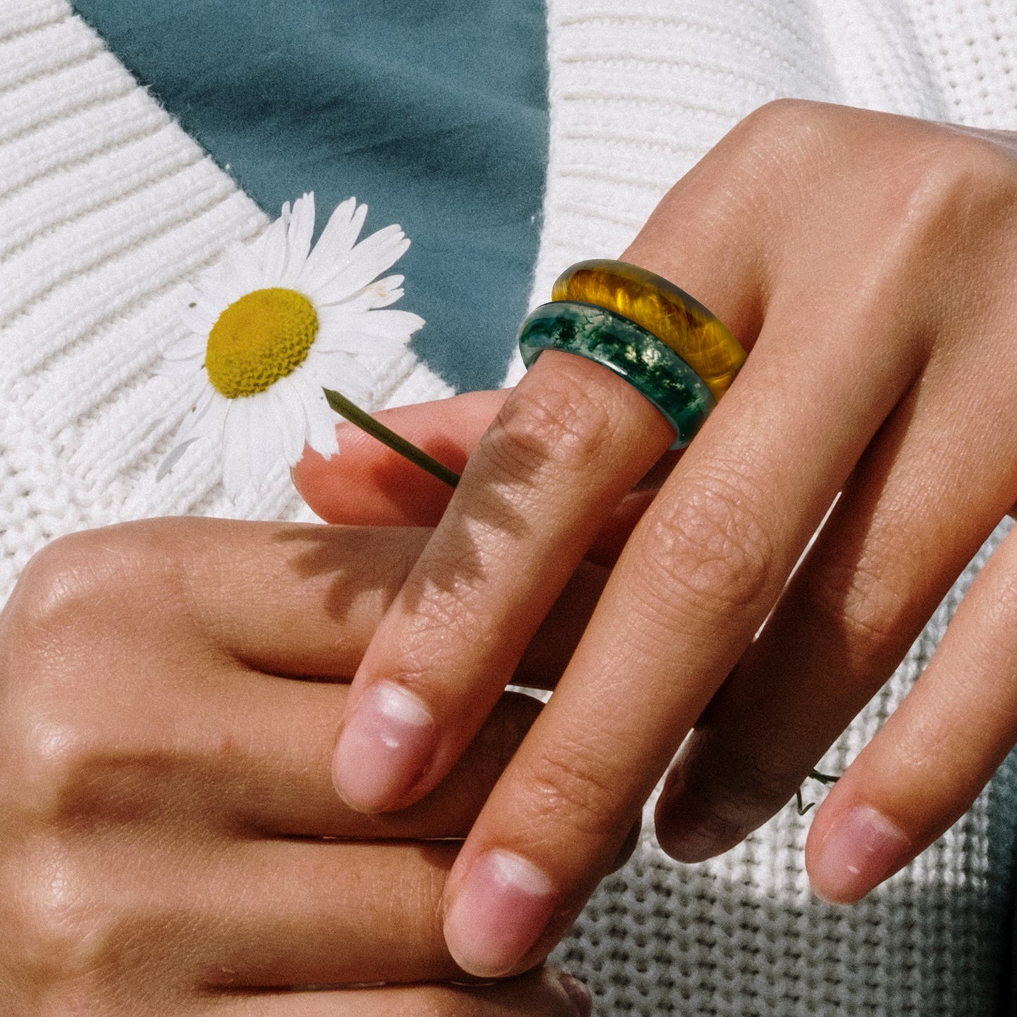 woman holding a flower while wearing carmela moss agate and toltec tiger's eye rings by whitestone jewelry co.