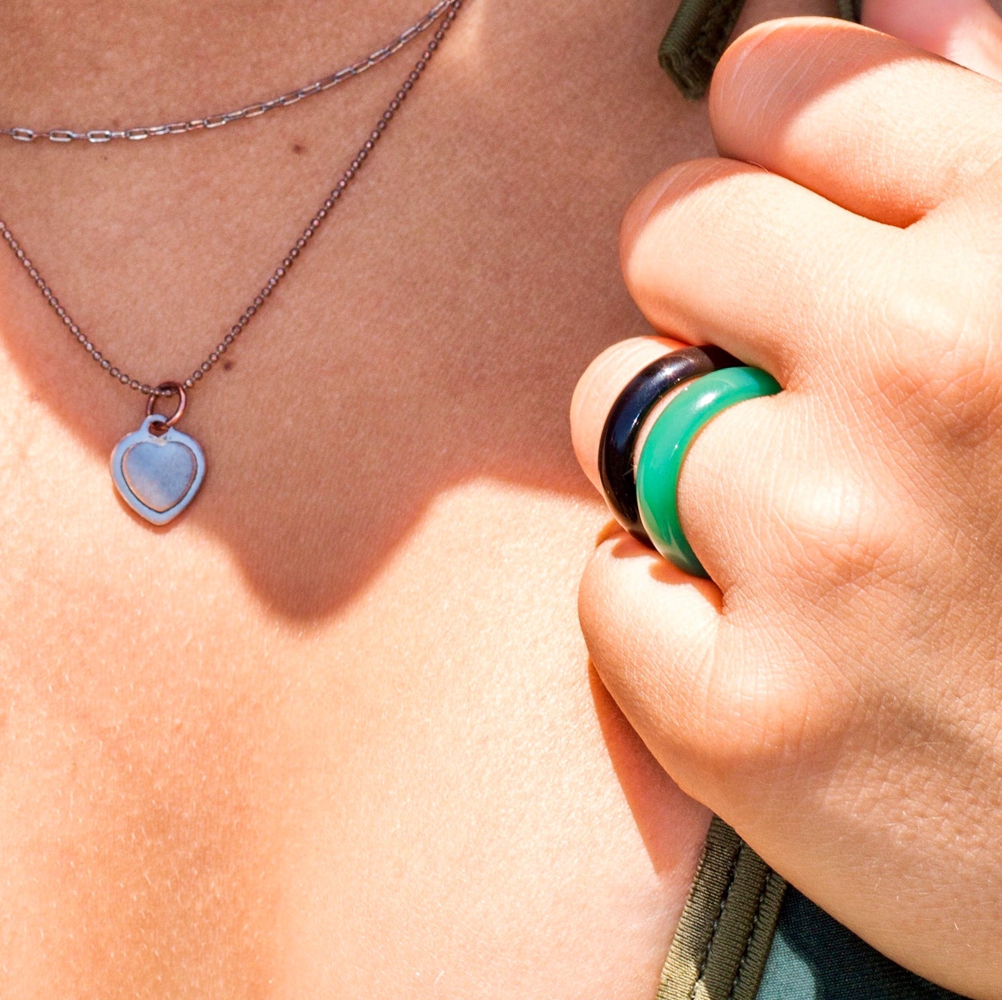 black onyx and green agate rings paired on woman's hand, closeup near neck, by whitestone jewelry co.