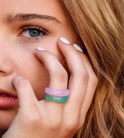 pink agate and light green agate rings paired together on a woman's hand, her hand is resting on her face, by whitestone jewelry co.
