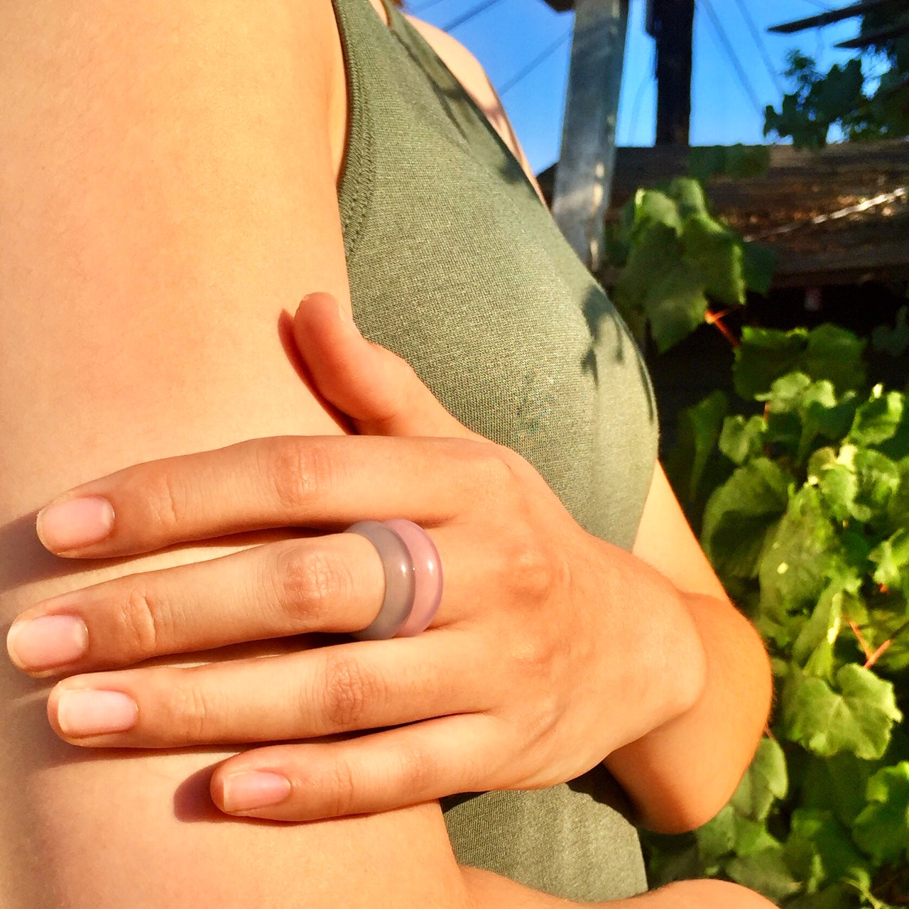 blue agate and pink agate rings paired together on woman's hand with grape vines in the background, by whitestone jewelry co.