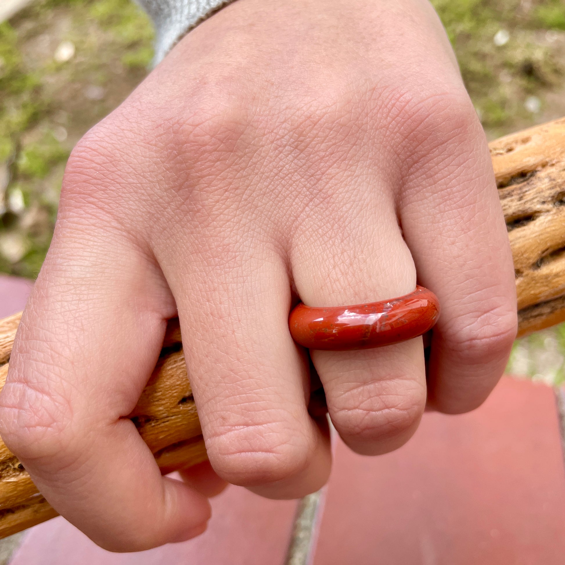 red jasper ring on woman's hand holding a piece of wood, by whitestone jewelry co.