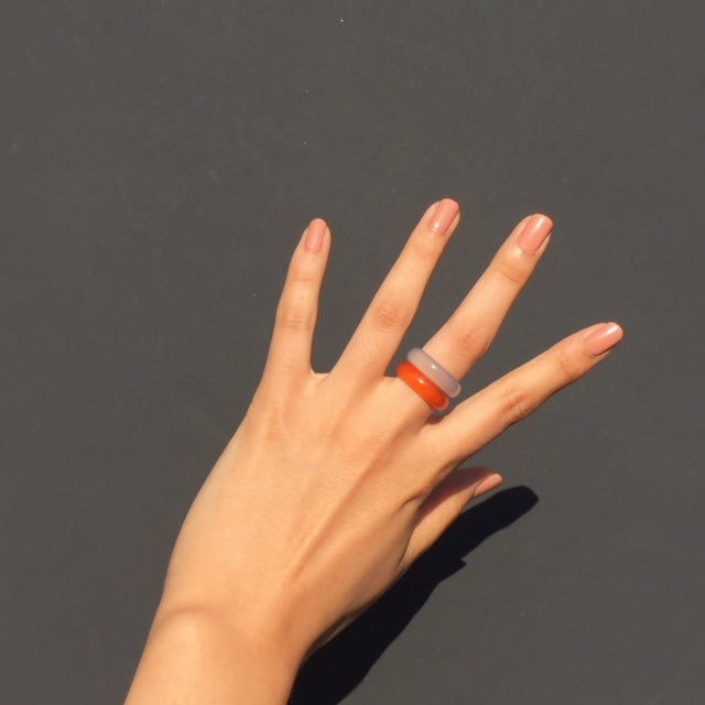 white agate and orange agate rings paired on woman's hand with black background, by whitestone jewelry co.