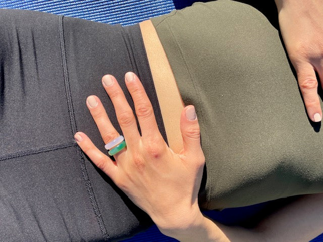 woman wearing yoga clothes lying on yoga mat while wearing white agate chakra ring ring from whitestone jewelry co.