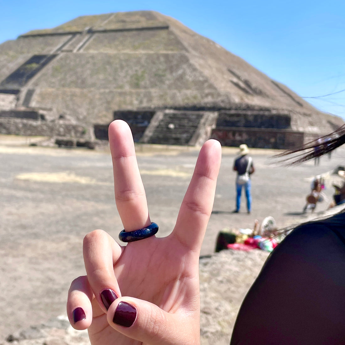 woman making a peace sign with fingers while wearing stone ring on finger posing at the Teotihuacan ruins in Mexico