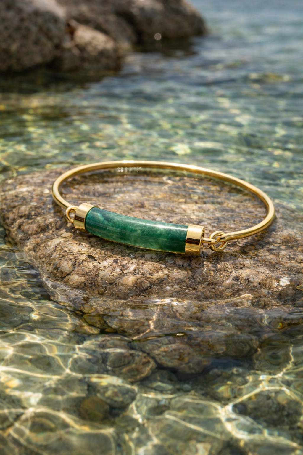 Jade and gold vintage tension cuff on rock in water 