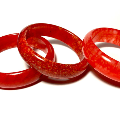 Three chicken blood red bangles stacked on a white background