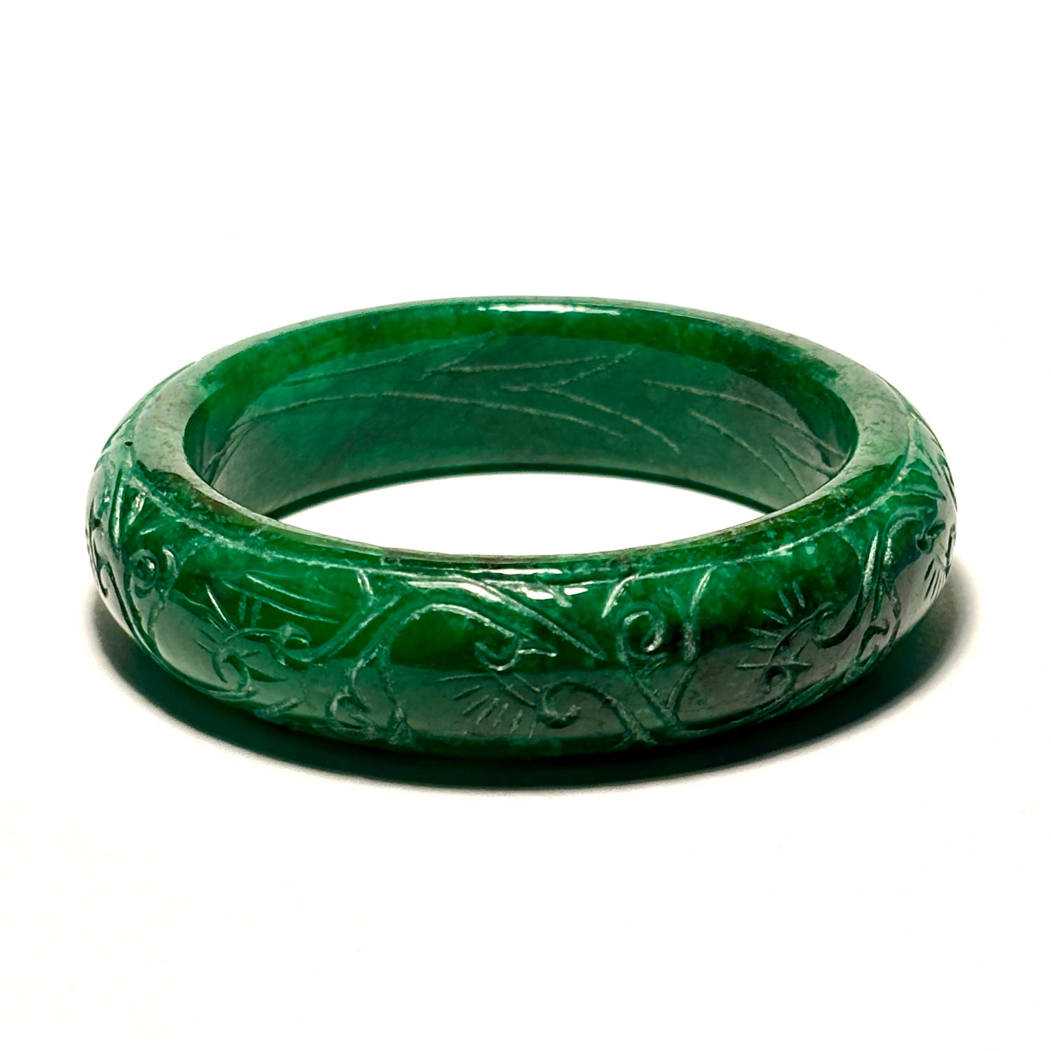 Green jade ring with intricate carvings on a white background