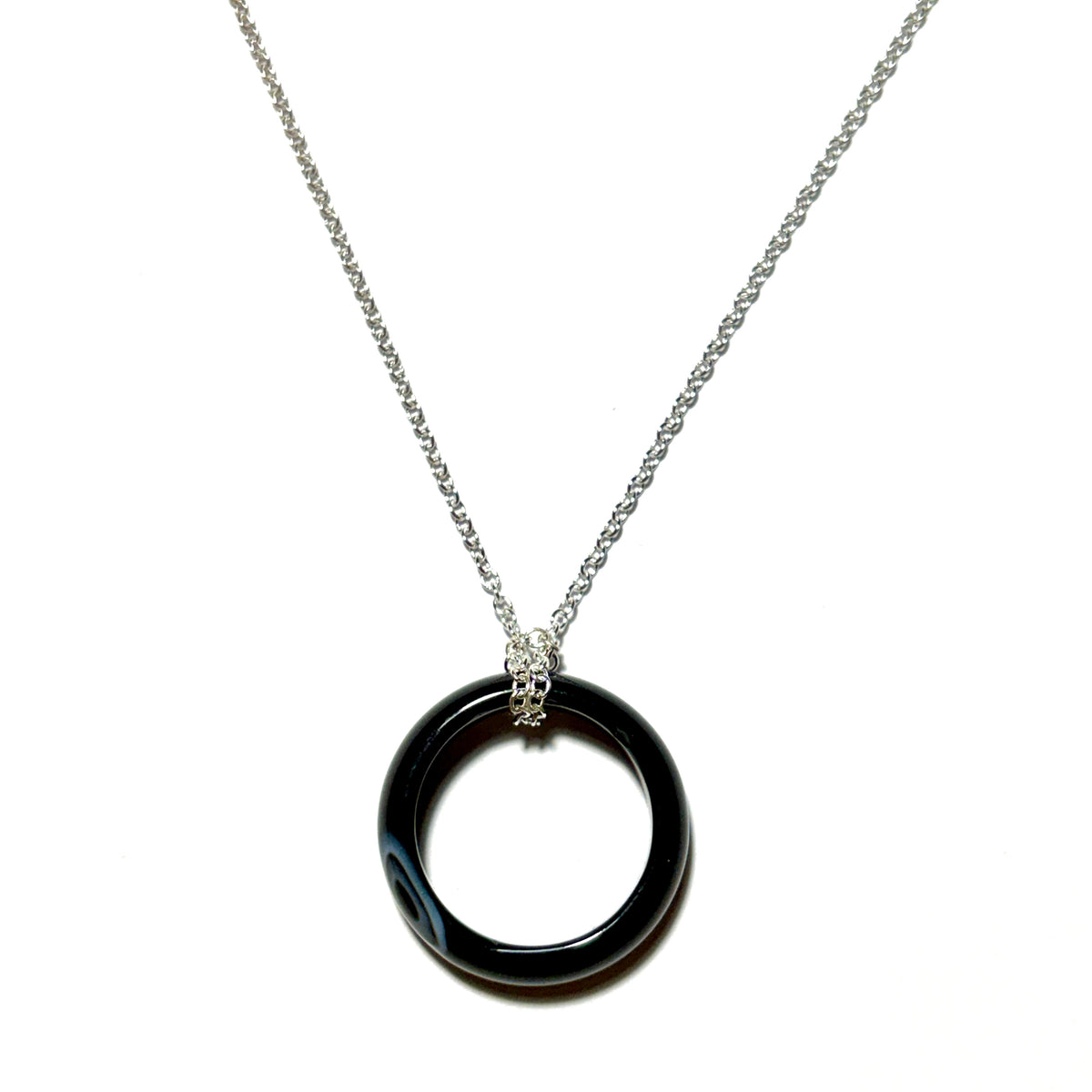 A silver chain necklace featuring a polished black circular ring pendant with a textured silver bail, shown against a plain white background.