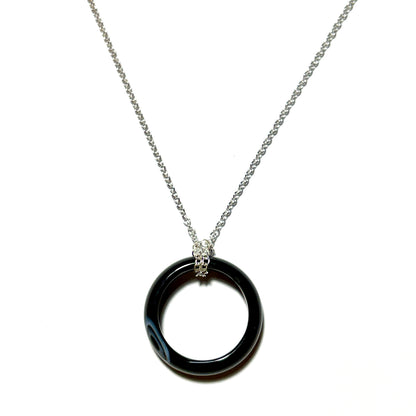 A silver chain necklace featuring a polished black circular ring pendant with a textured silver bail, shown against a plain white background.