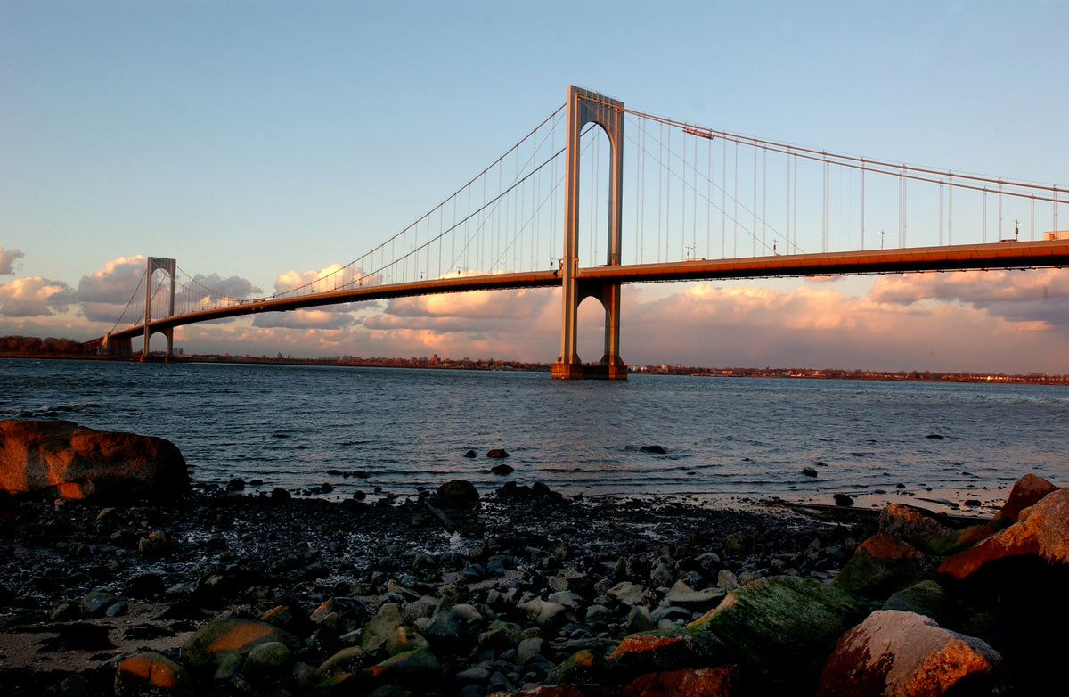 Whitestone Bridge over water with rocky shore and sunset sky