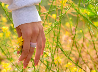 pink agate and blue agate rings paired together on a woman's hand, holding yellow flowers, by whitestone jewelry co.